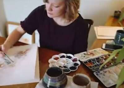Artist Jess Davis painting a bird in watercolor at her desk